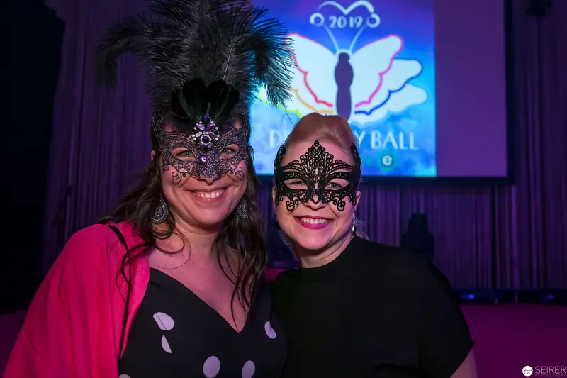 Two Masked Attendees at Formal Masquerade Ball with Butterfly Projection