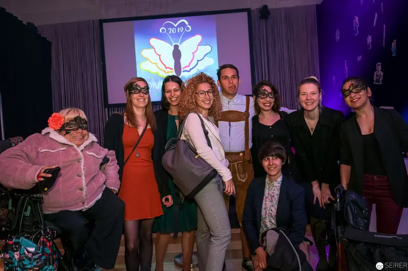 Diverse Group Pose at Butterfly-Themed Event with Projector Backdrop