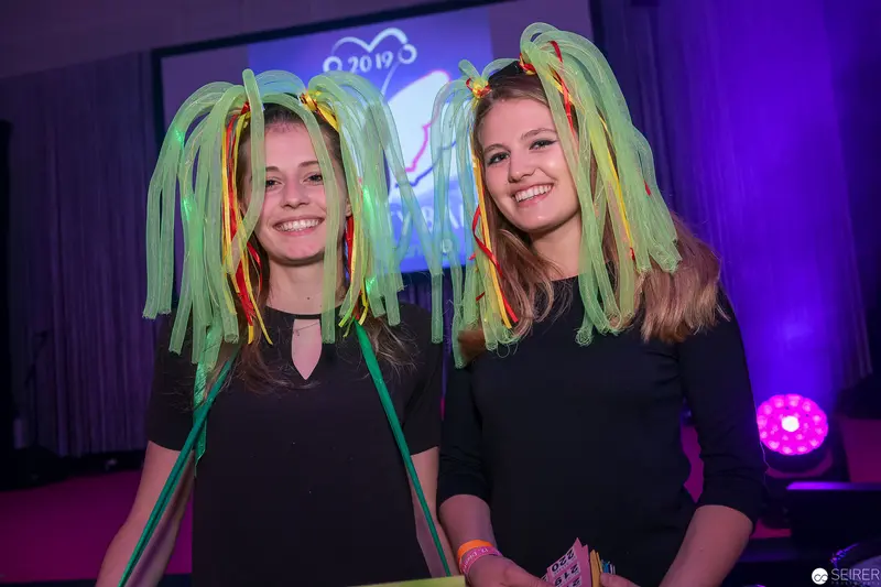Two Smiling Women with Neon Green Light-Up Hair at Festive Event