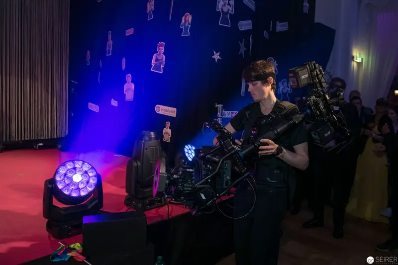 Cinematographer Operating Professional Camera Equipment Under Dramatic Stage Lighting