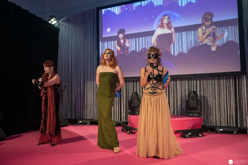 Theatrical Fashion Showcase with Performers on Pink Stage Backdrop