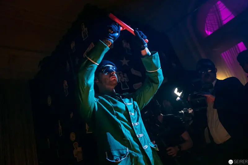 Performer in Blue and Green Stage Lighting Raising Illuminated Object