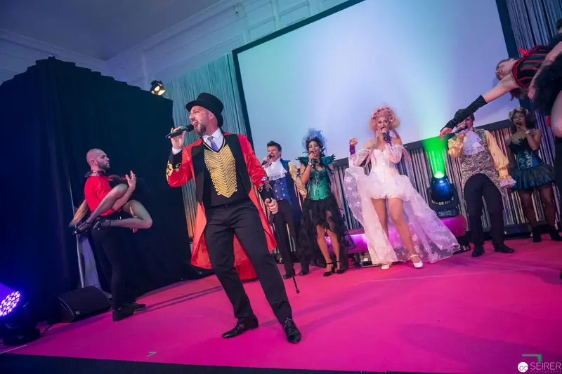 Theatrical Ringmaster Performance with Ensemble on Vibrant Pink Stage