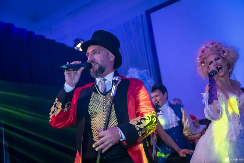 Theatrical Performance with Ringmaster and Chorus in Vibrant Stage Lighting
