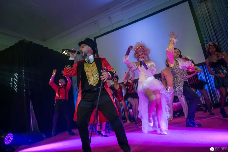 Theatrical Musical Performance with Costumed Performers on Vibrant Magenta-Lit Stage