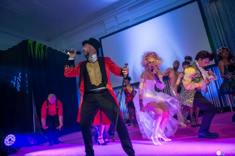 Theatrical Performance with Ringmaster and Ensemble in Vibrant Stage Lighting