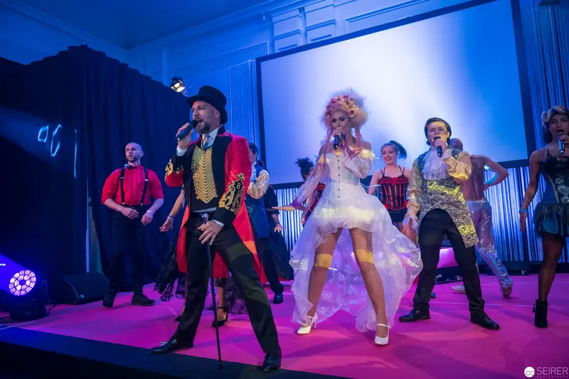 Theatrical Performance with Ringmaster and Ensemble in Vibrant Stage Lighting