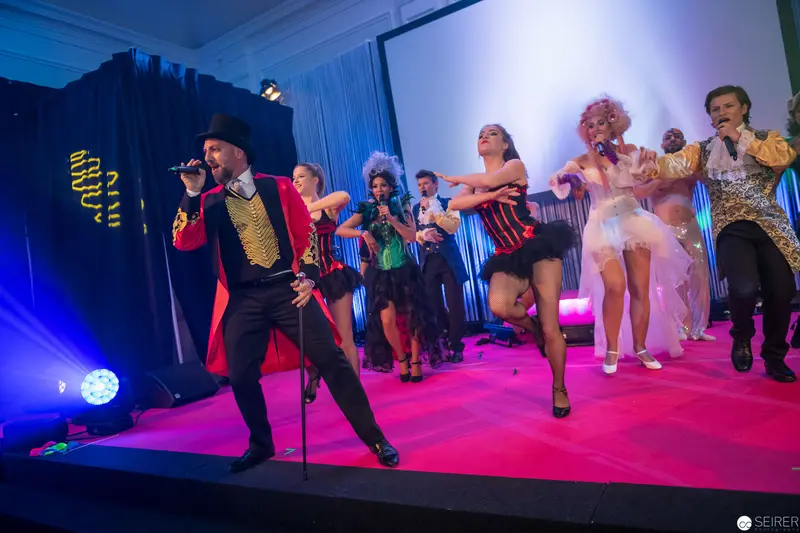 Theatrical Performance with Lead Singer in Ringmaster-Inspired Costume on Pink Stage