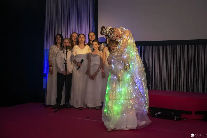 Illuminated Performance with Choir in Ethereal White Gowns on Stage