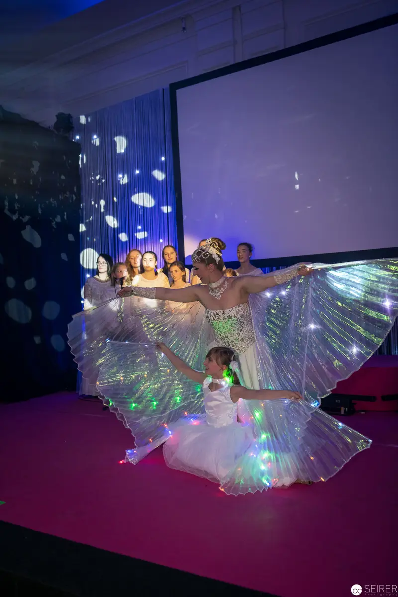 Luminescent Performance with Glowing Fabric Wings on Pink Stage