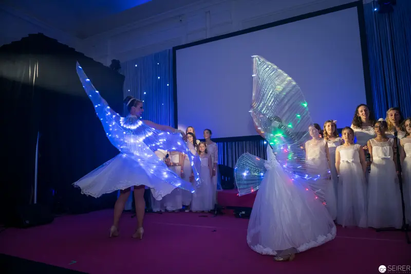 Illuminated Dancers in White Performance with Glowing Wing-like Costumes
