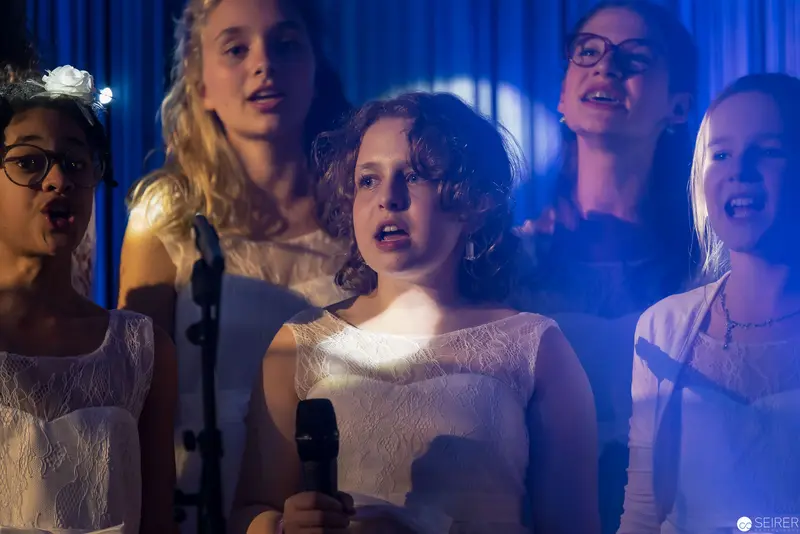 Youth Choir Performance Under Blue Stage Lighting with Microphones