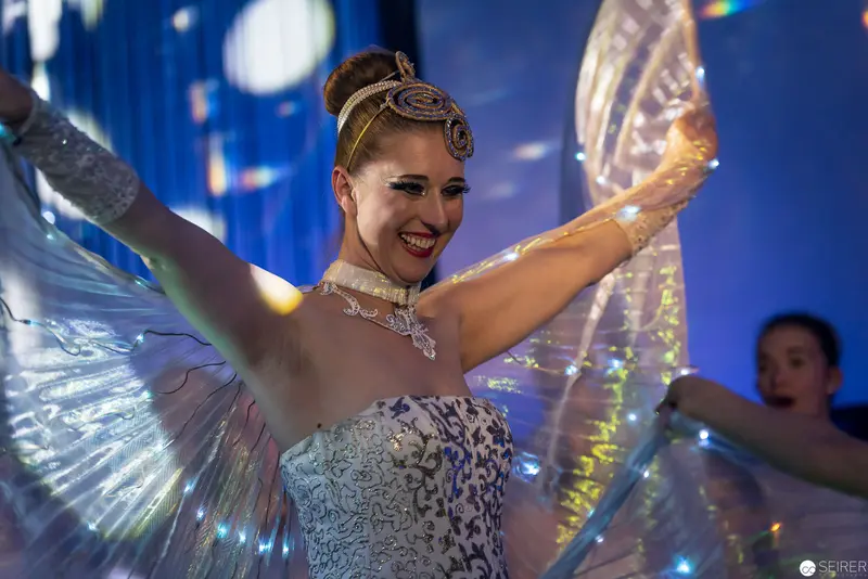 Performance Artist in Iridescent Costume Celebrating with Outstretched Wing-Like Accessories