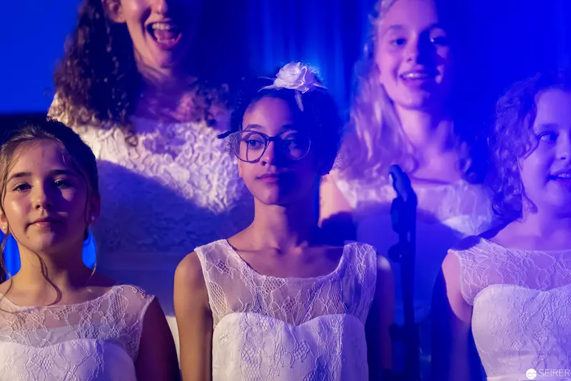 Young Choir Ensemble in White Lace Performing Under Blue Stage Lighting