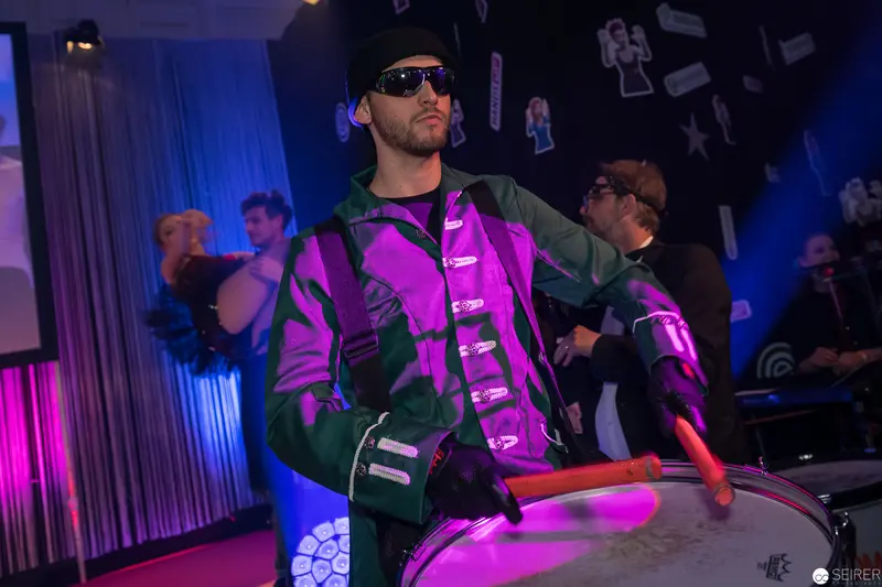 Percussionist in Purple and Green Under Dramatic Stage Lighting