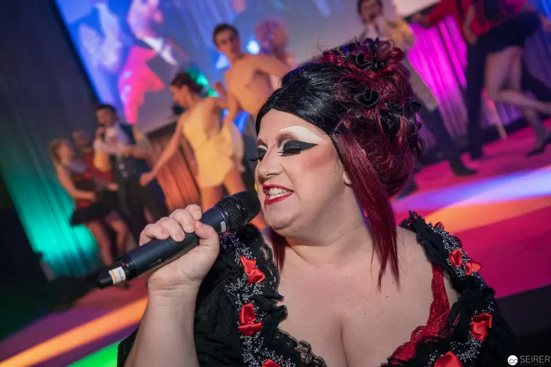 Drag Performance with Dramatic Makeup and Microphone on Colorful Stage