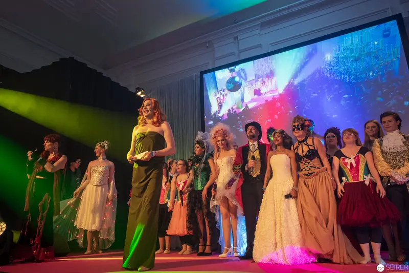 Fashion Show Finale with Diverse Performers on Colorfully Illuminated Stage