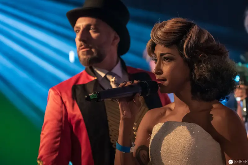 Vintage Nightclub Scene with Singer in Sparkling White Dress and Performer in Red Jacket