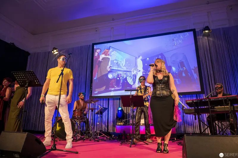 Live Music Performance with Vocalists on Pink Stage Under Blue Lighting