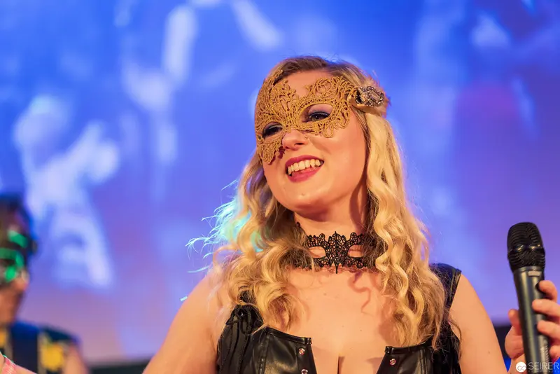 Blonde Performer in Ornate Mask Singing at Theatrical Performance
