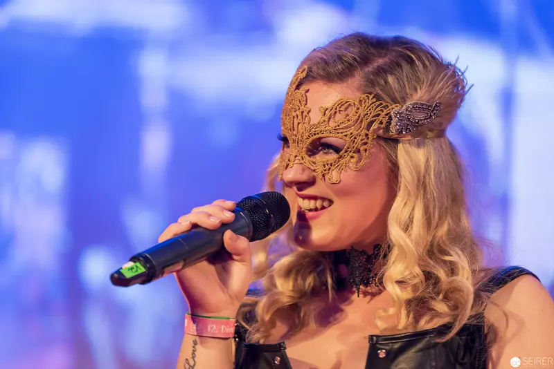 Masked Singer Performs with Ornate Gold Lace Mask Under Blue Stage Lighting