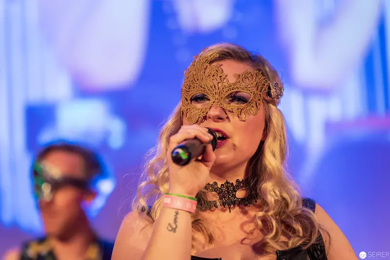 Masked Performer Singing with Intricate Golden Mask at Musical Event