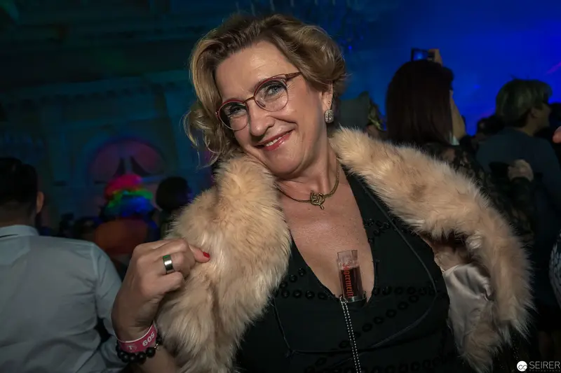 Mature Woman in Fur Coat Smiling at Nighttime Social Event