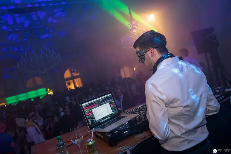 Electronic Dance Music DJ Performing at Nightclub with Colored Lighting and Crowd