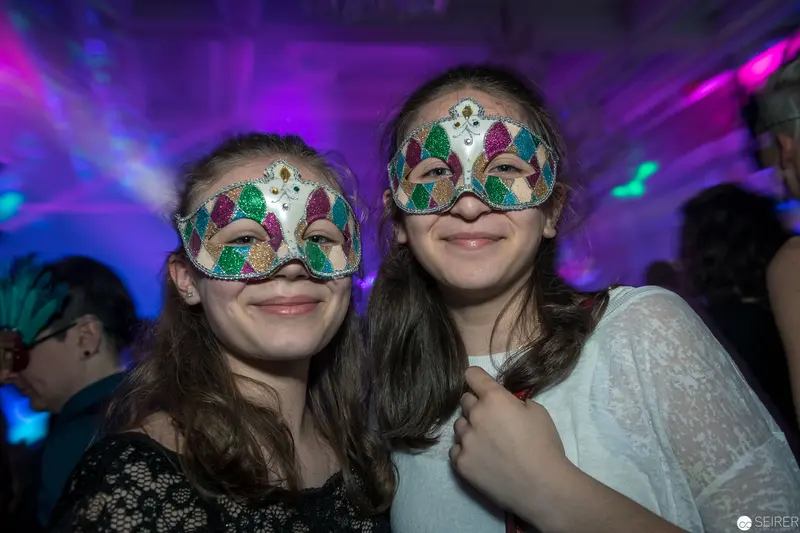 Two Young Women in Ornate Masquerade Masks at Festive Evening Event