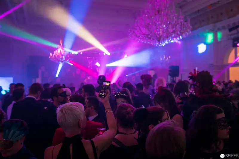 Crowded Nightclub Scene with Colorful Stage Lighting and Chandelier