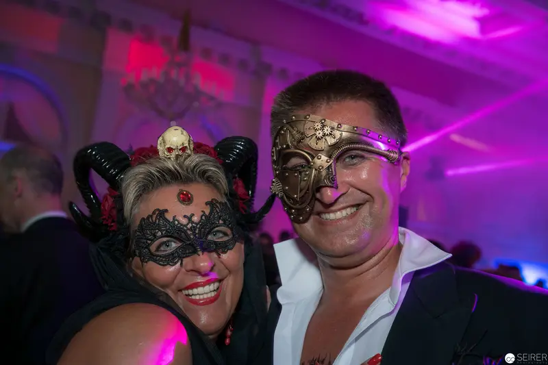Masquerade Ball Revelers in Ornate Masks Under Purple Lighting