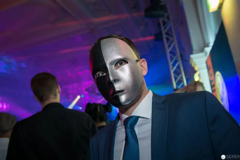 Silver-Masked Figure in Blue Suit at Nighttime Corporate or Entertainment Event
