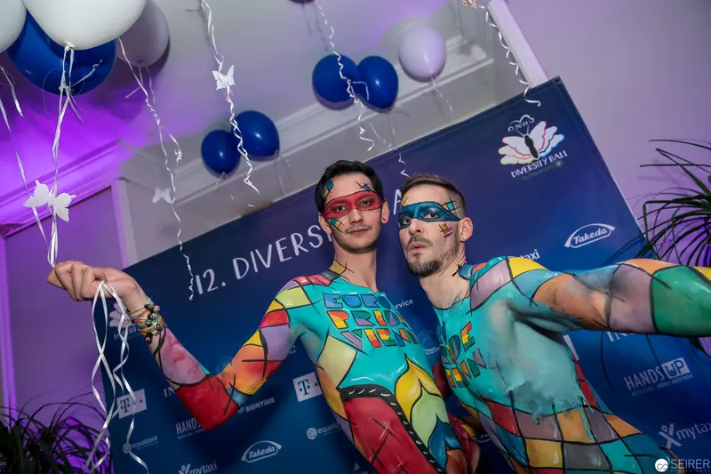 Two Performers in Colorful Body Art at Diversity Event with Festive Backdrop