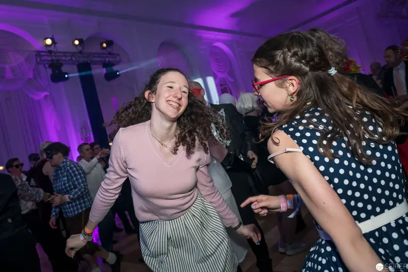 Young Women Dancing with Exuberant Movement in Purple-Lit Event Space