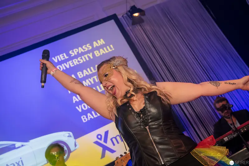 Dynamic Female Performer Energizing University Ball Stage with Microphone and Enthusiasm