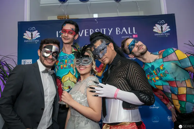 University Ball Masquerade: Five Guests Posing in Elaborate Masks and Festive Attire