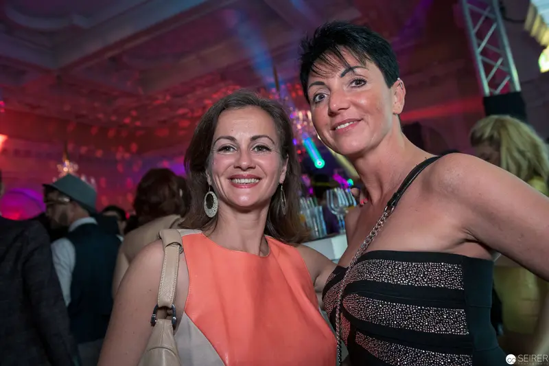 Two Women in Festive Evening Attire at Vibrant Social Event