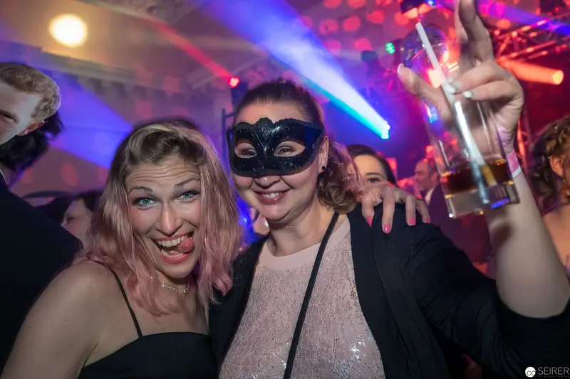 Masked Revelry: Two Women Celebrating at Nightclub Party with Vibrant Lighting