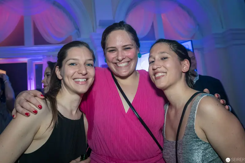 Three Women in Festive Lighting at Social Gathering