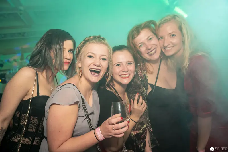 Five Young Women Celebrating at Nightclub with Turquoise Atmospheric Lighting
