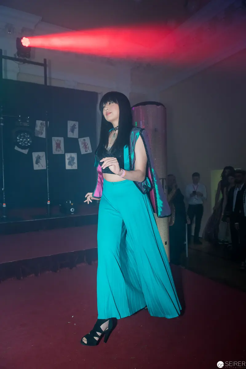 Performer in Turquoise Wide-Leg Pants Under Red Stage Lighting