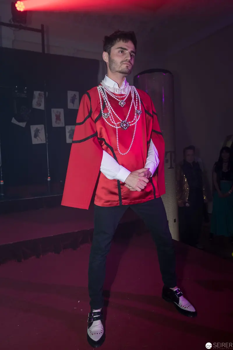 Performance in Crimson: Staged Figure in Red Cape and Layered Necklaces