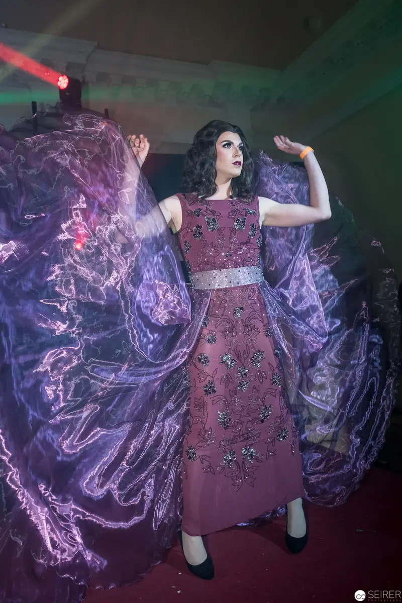 Performance in Purple: Dramatic Stage Pose with Swirling Ethereal Fabric