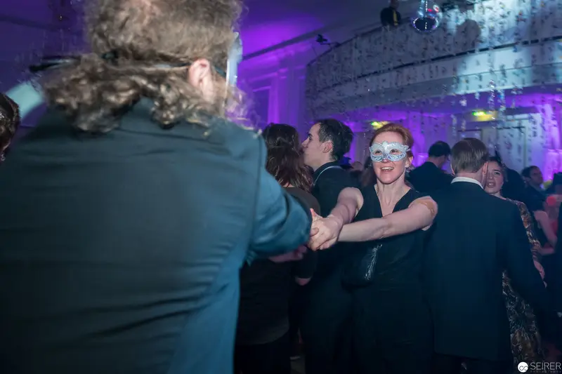 Masquerade Dance Floor: Festive Evening with Guests in Purple-Lit Venue