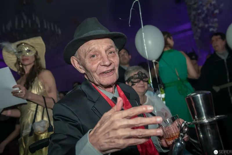 Elderly Gentleman in Festive Party Scene with Cocktail and Balloon