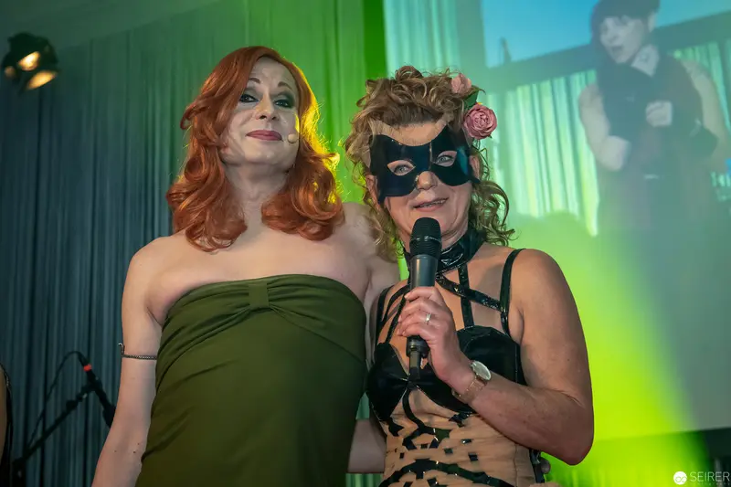 Two Performers in Masked Performance with Green Stage Lighting