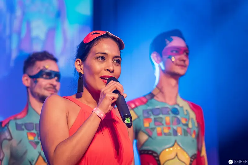 Performer in Coral Top Singing on Stage with Colorful Backdrop