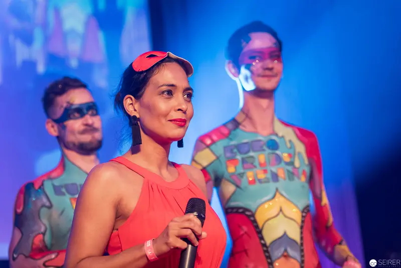 Performers in Vibrant Coral and Geometric Costumes on Dynamic Stage
