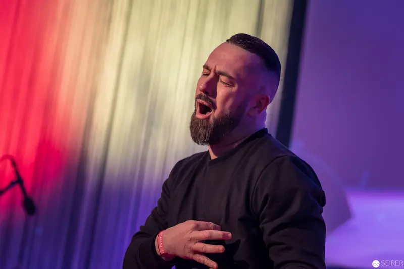 Emotional Performer in Dramatic Stage Lighting, Hand on Heart