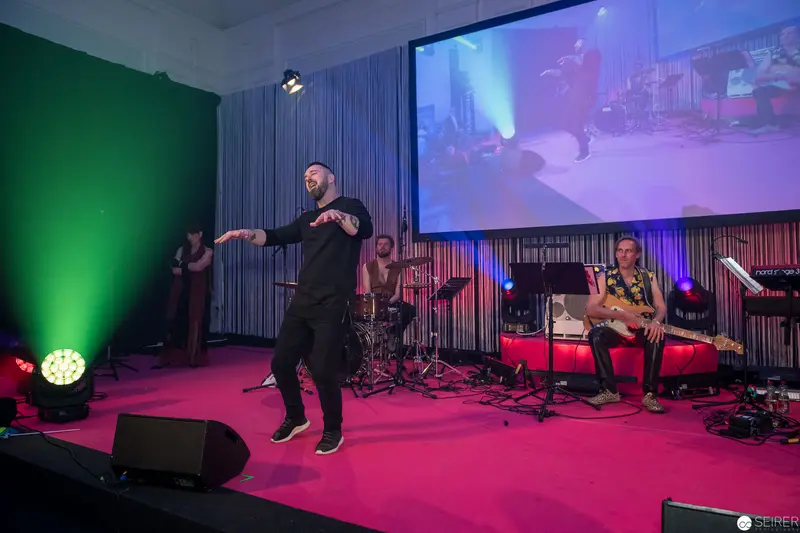 Live Music Performance with Dynamic Singer on Pink Stage with Multicolored Lighting